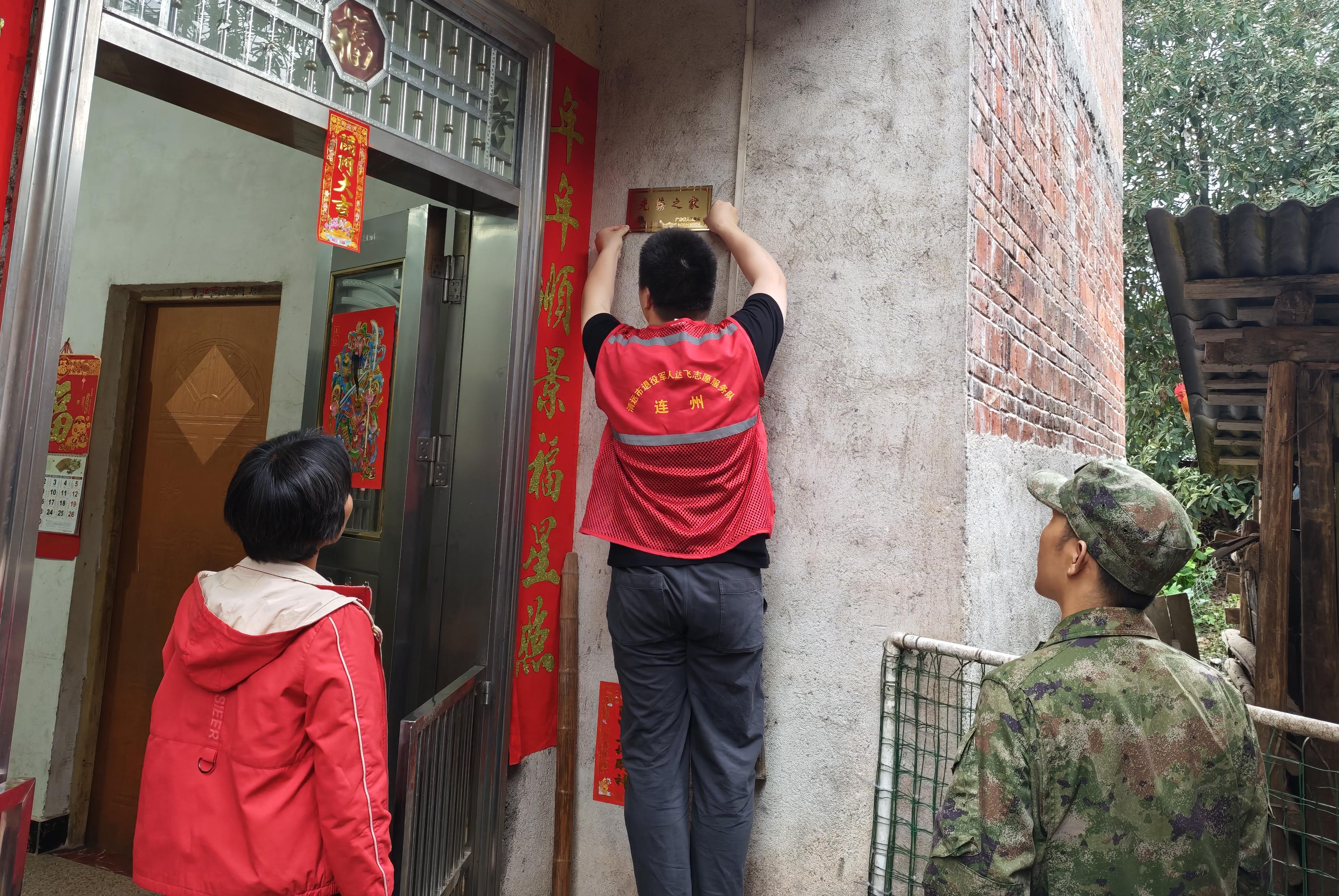 工作人员悬挂“光荣之家”牌匾。通讯员供图
